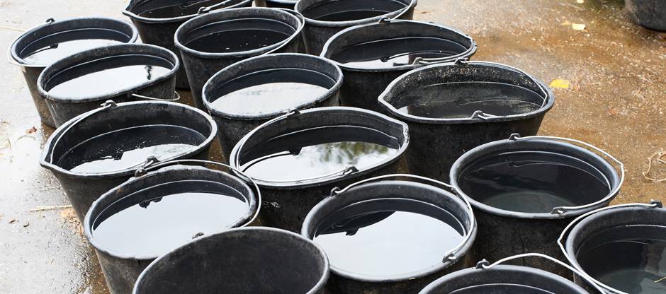 Full water buckets lined up in barn aisle